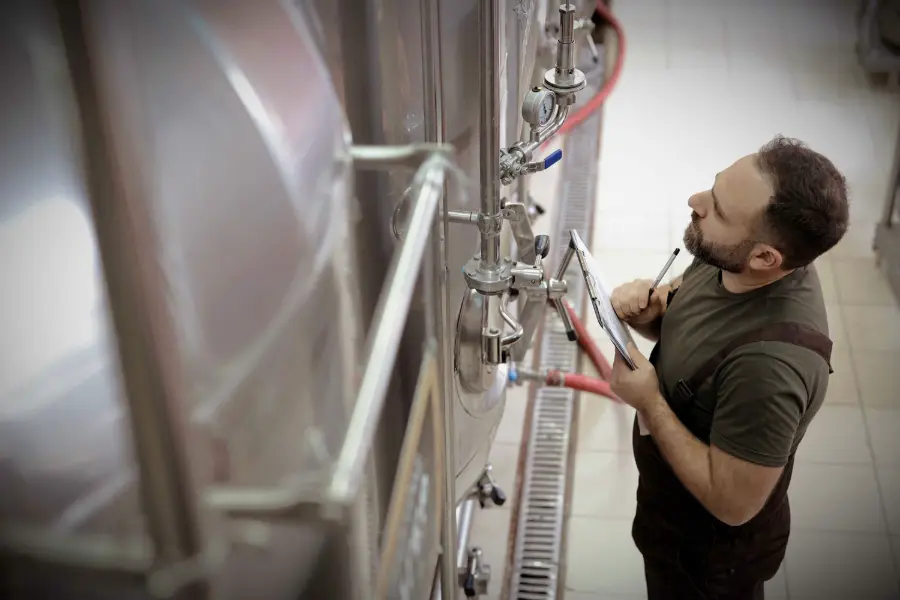 Técnico revisando la temperatura de un depósito de acero inoxidable durante el control de calidad